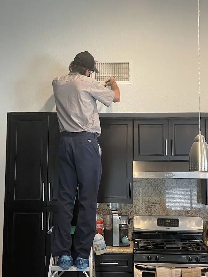 Technician inspecting an air vent during HVAC service in Harlingen